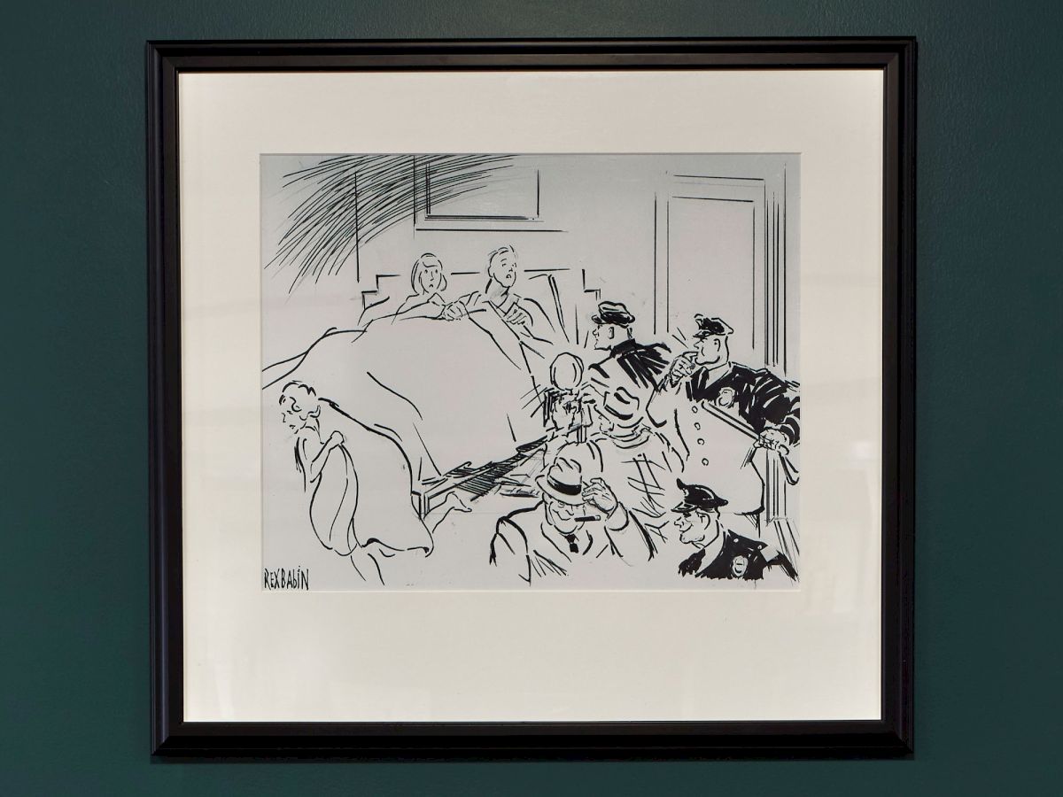 A framed black-and-white sketch shows several people in a room, with one seated and others gathered around in a lively scene.